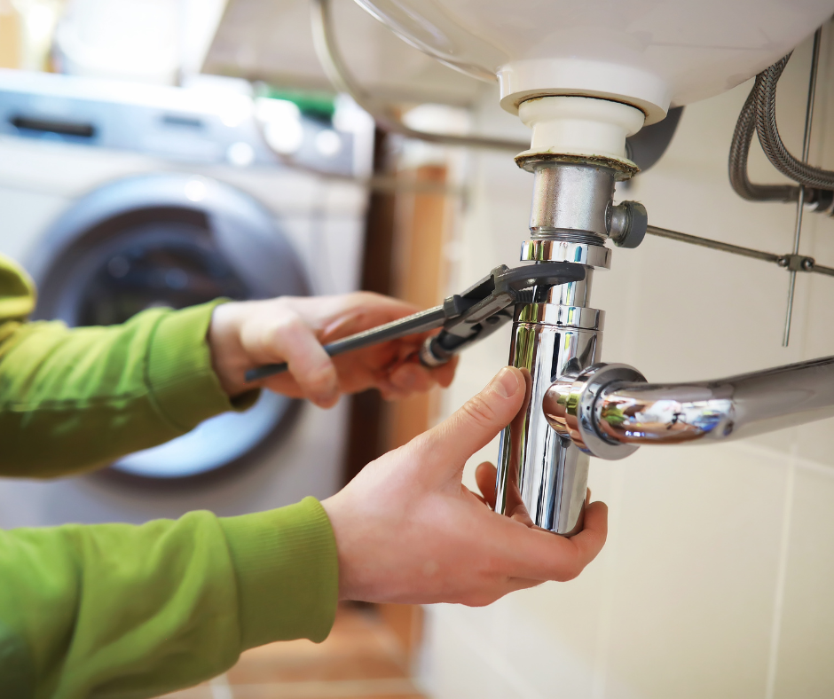Hands using pliers to tighten a chrome pipe under a sink