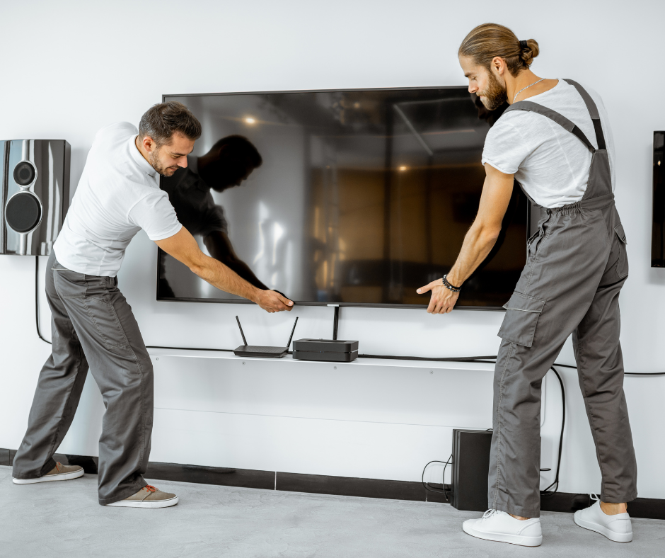 Two men installing a large TV on a white media console in a living room