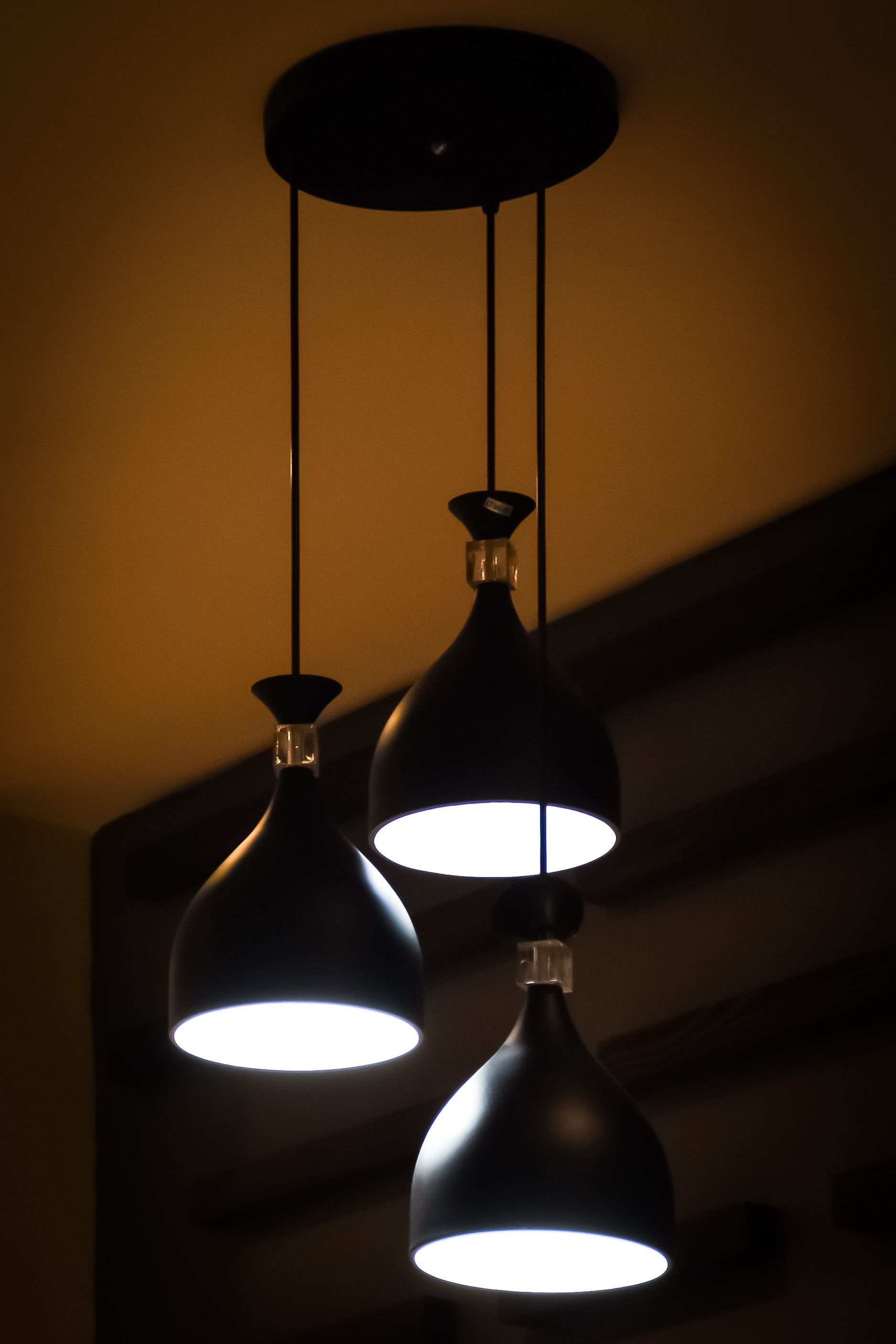 Three hanging pendant lights with white bulbs on a dark ceiling