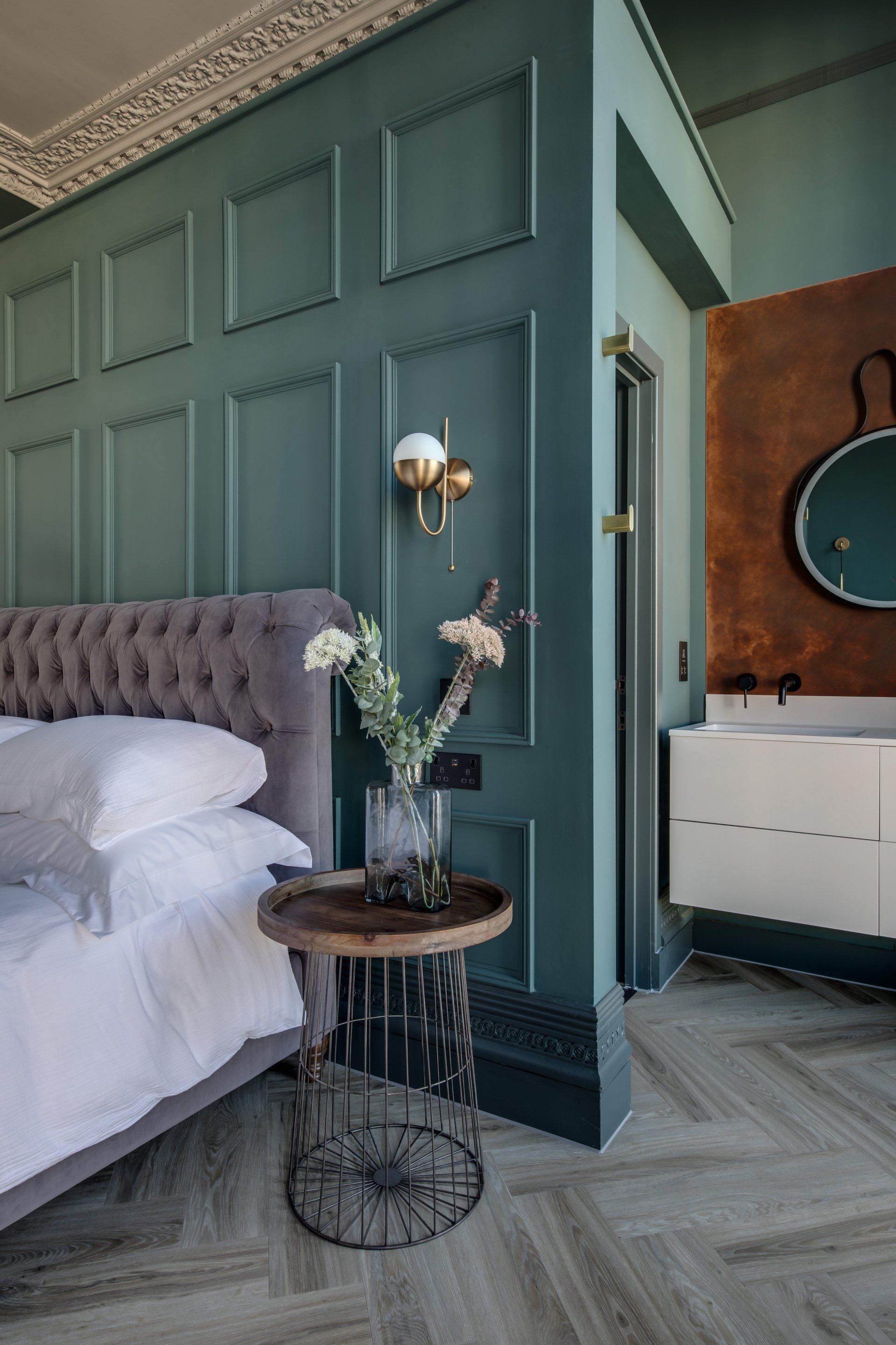 A bedroom with a bed , a table , a mirror and a bathroom.