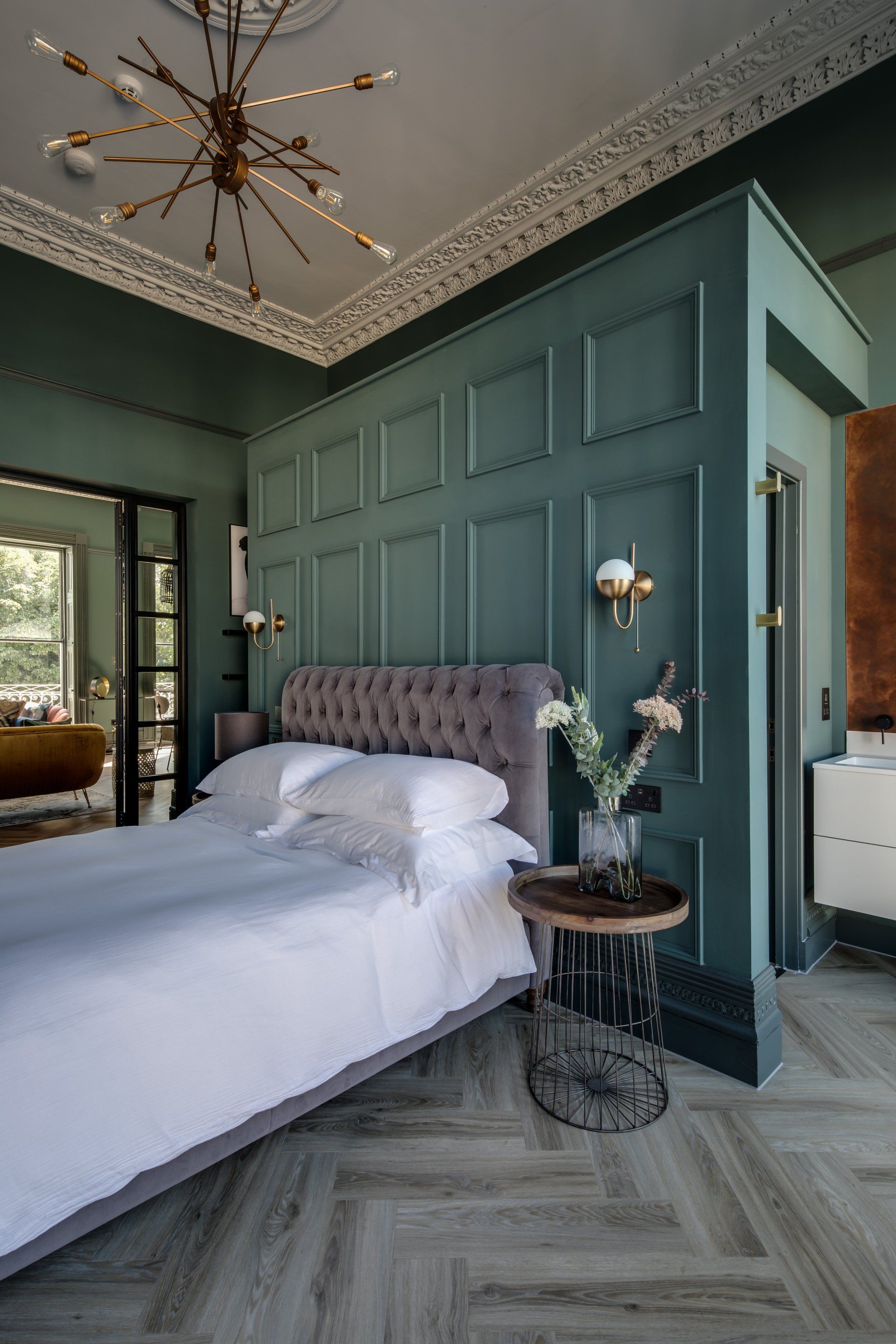 A bedroom with a bed , nightstand , and chandelier.