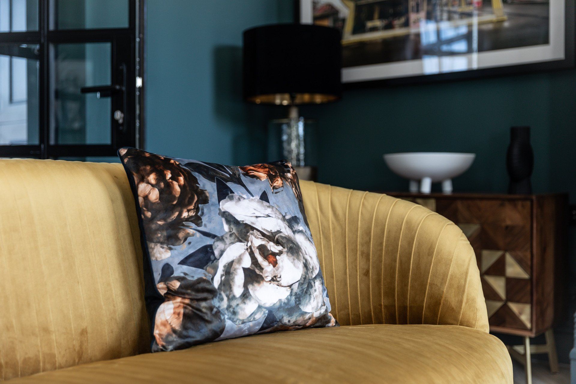 A yellow couch with a floral pillow on it in a living room.