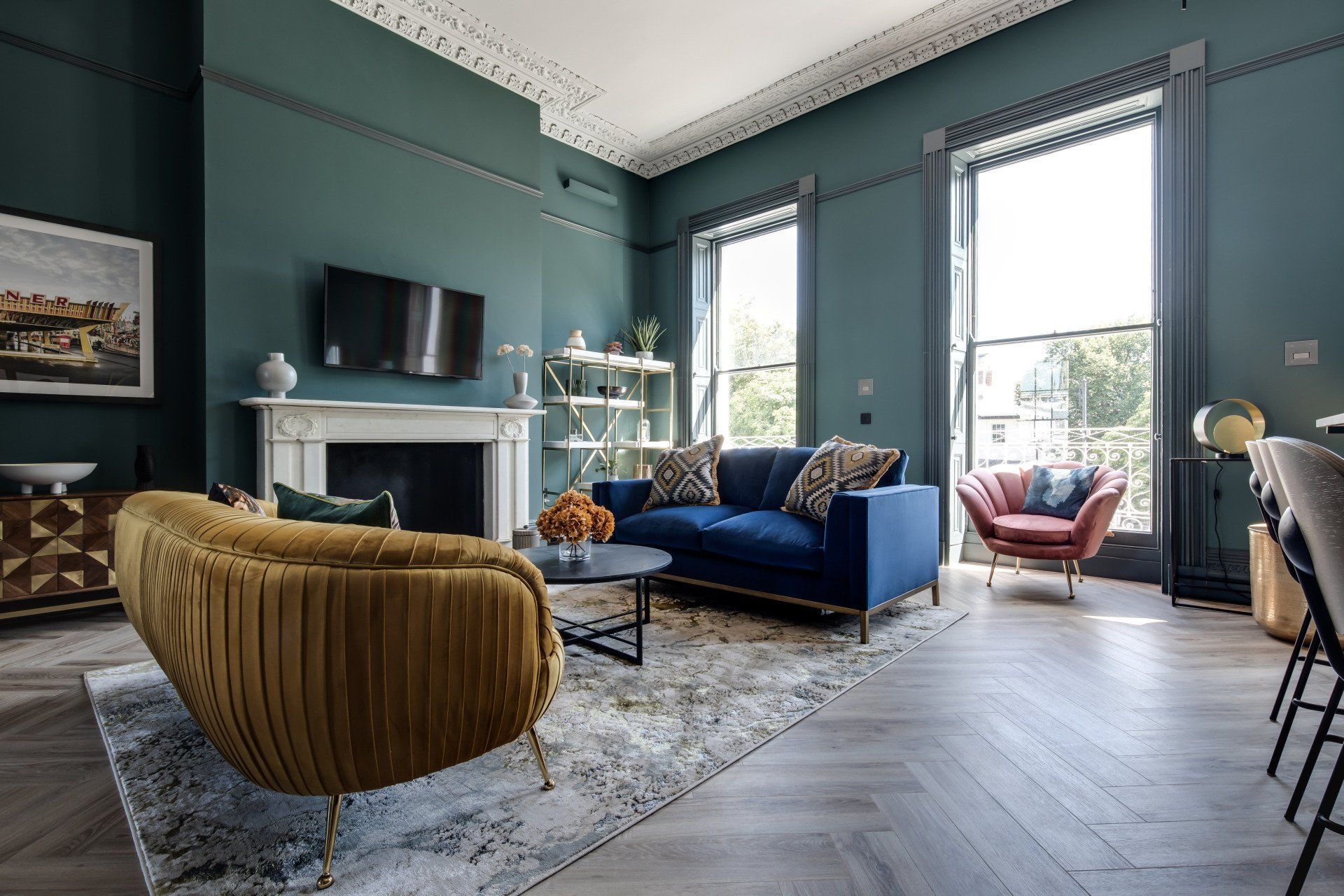 A living room with a blue couch , yellow chairs , and a fireplace.