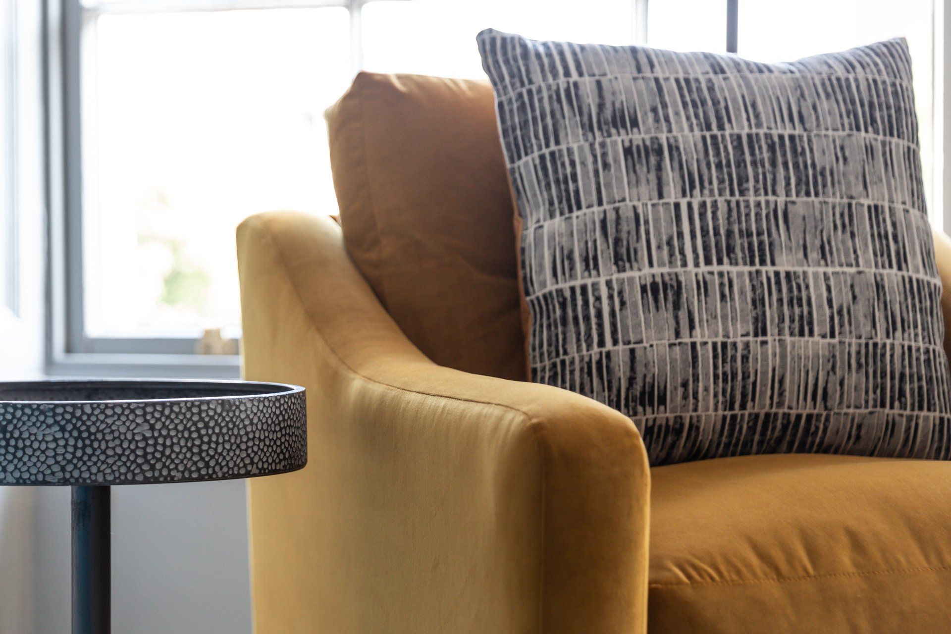 A yellow chair with a black and white pillow on it.