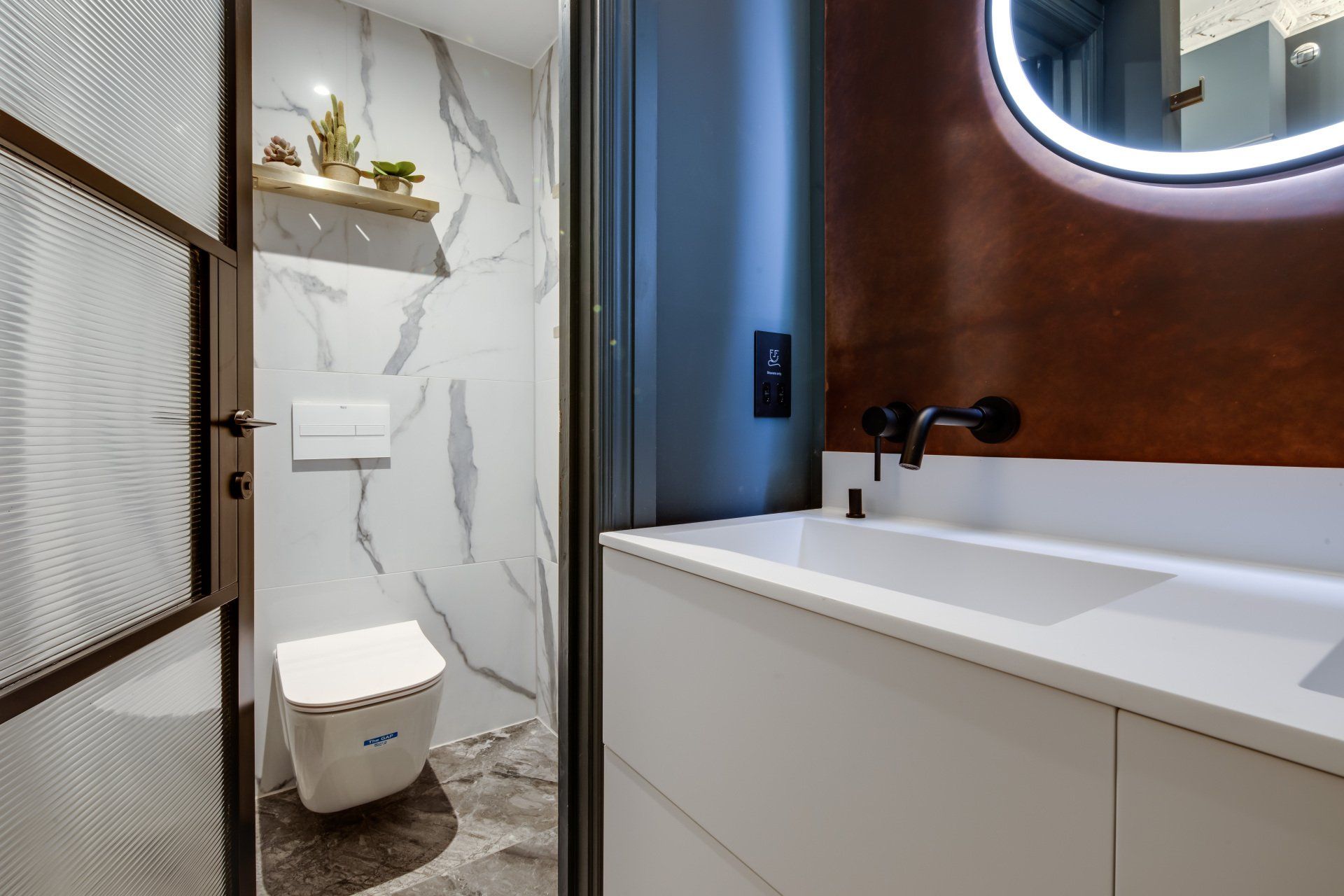 A bathroom with a toilet , sink and mirror.