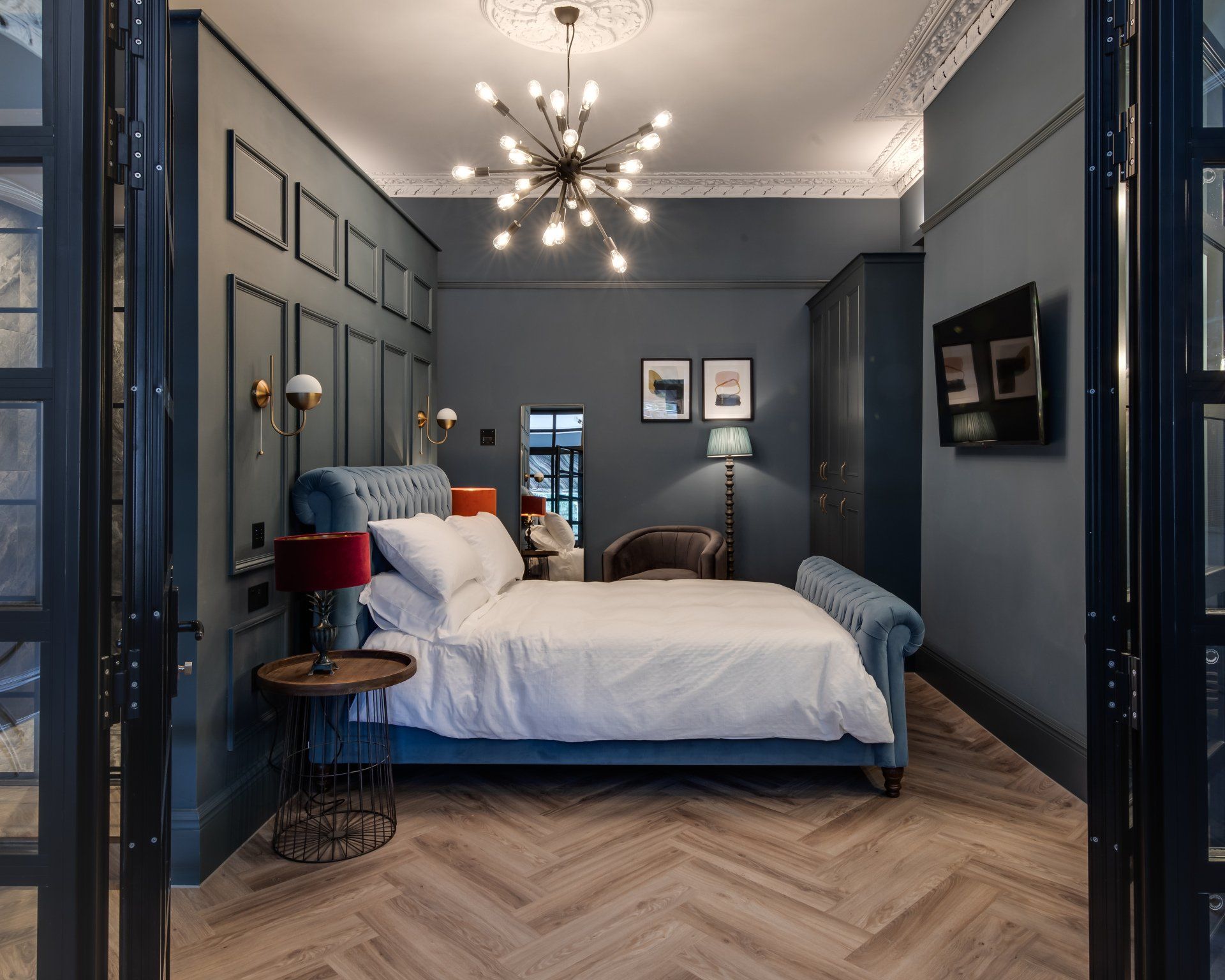A bedroom with a large bed and a television on the wall.