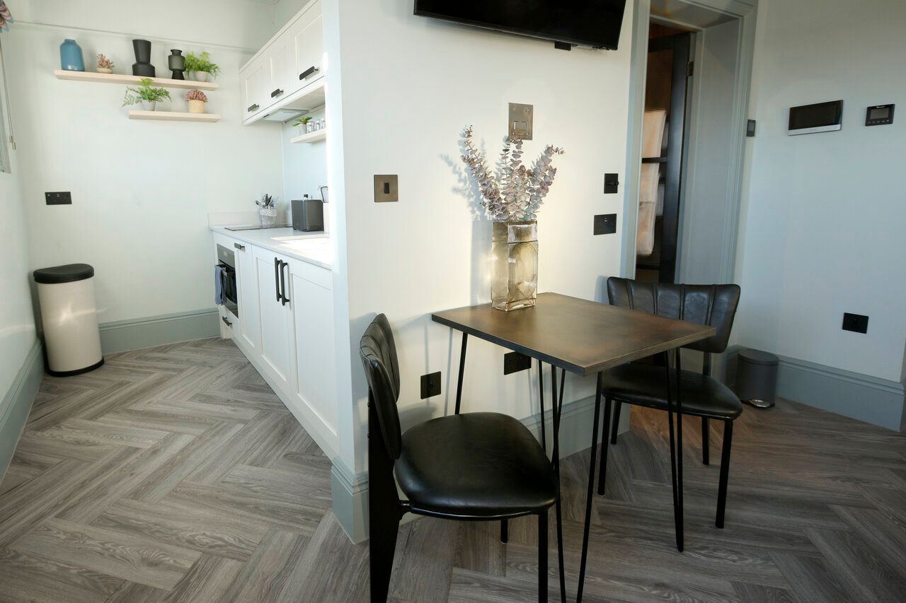 A kitchen with a table and chairs and a vase of flowers on the table.