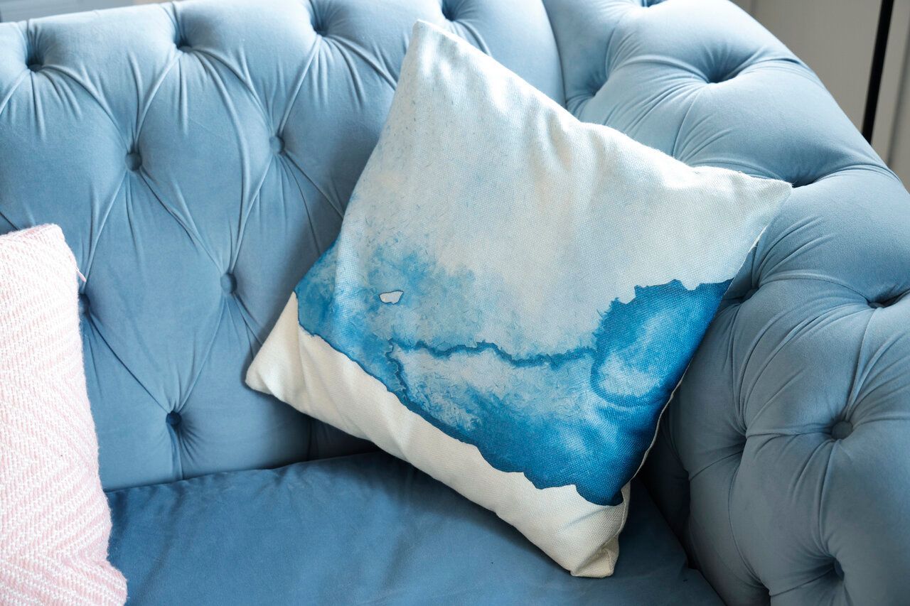A blue couch with a blue and white pillow on it.