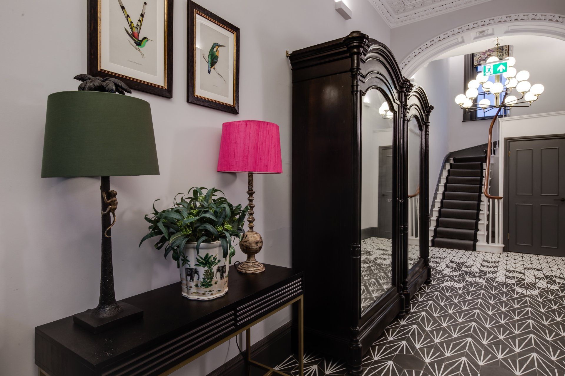 A hallway with a table and lamps and a staircase