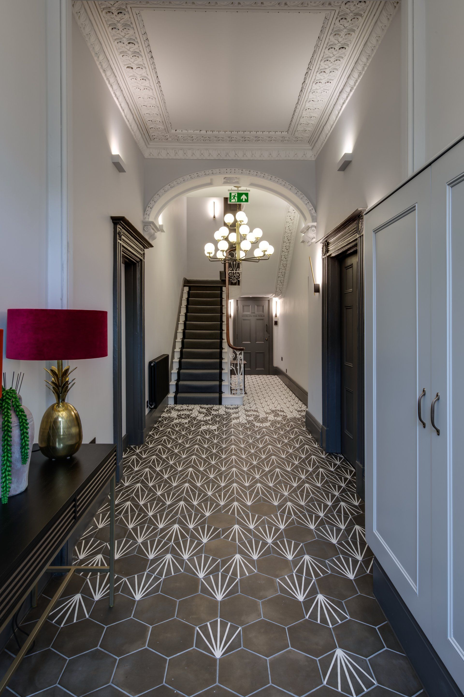 A hallway with a staircase and a table with a lamp on it.