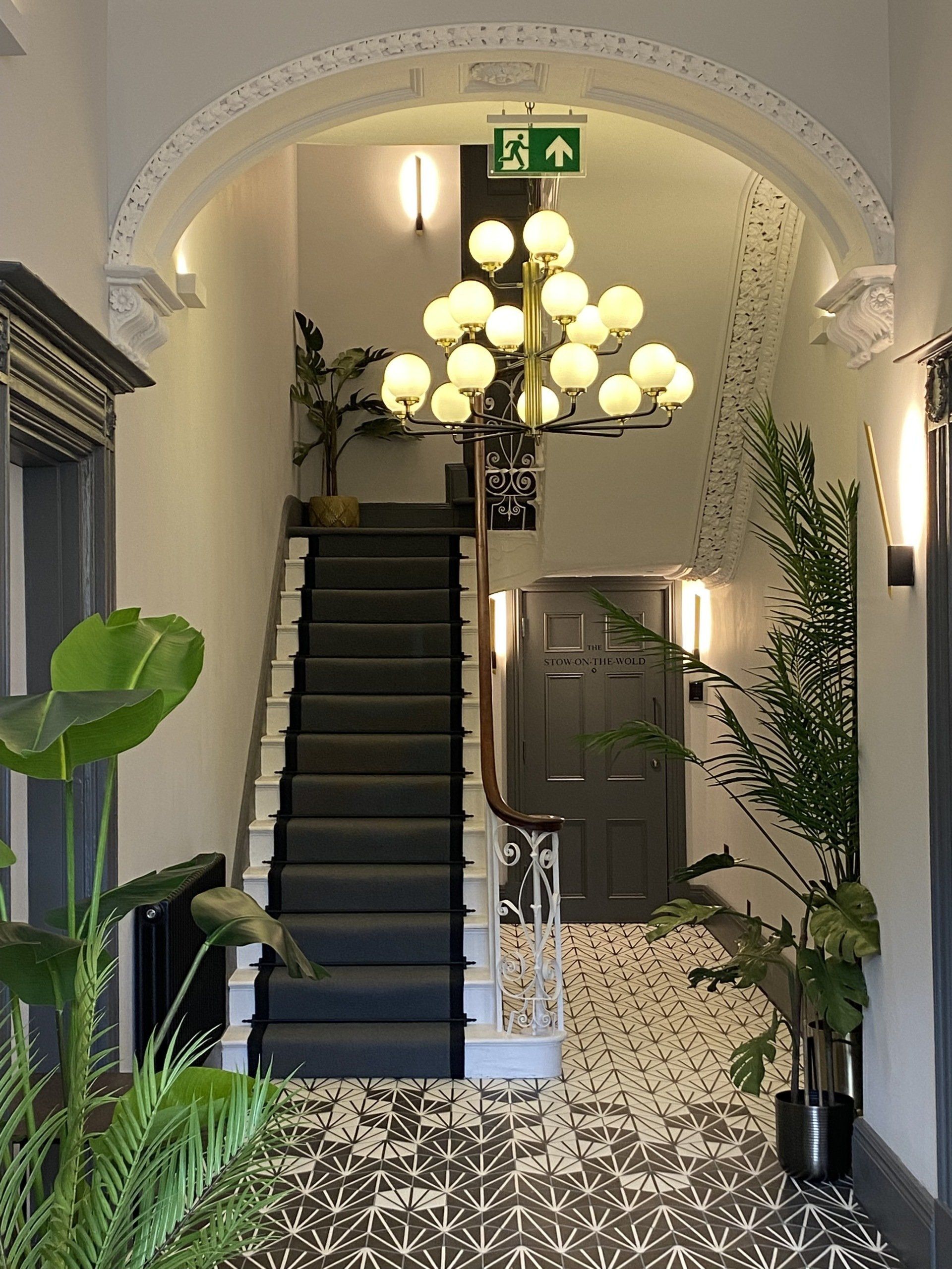 A staircase in a building with a chandelier hanging from the ceiling.