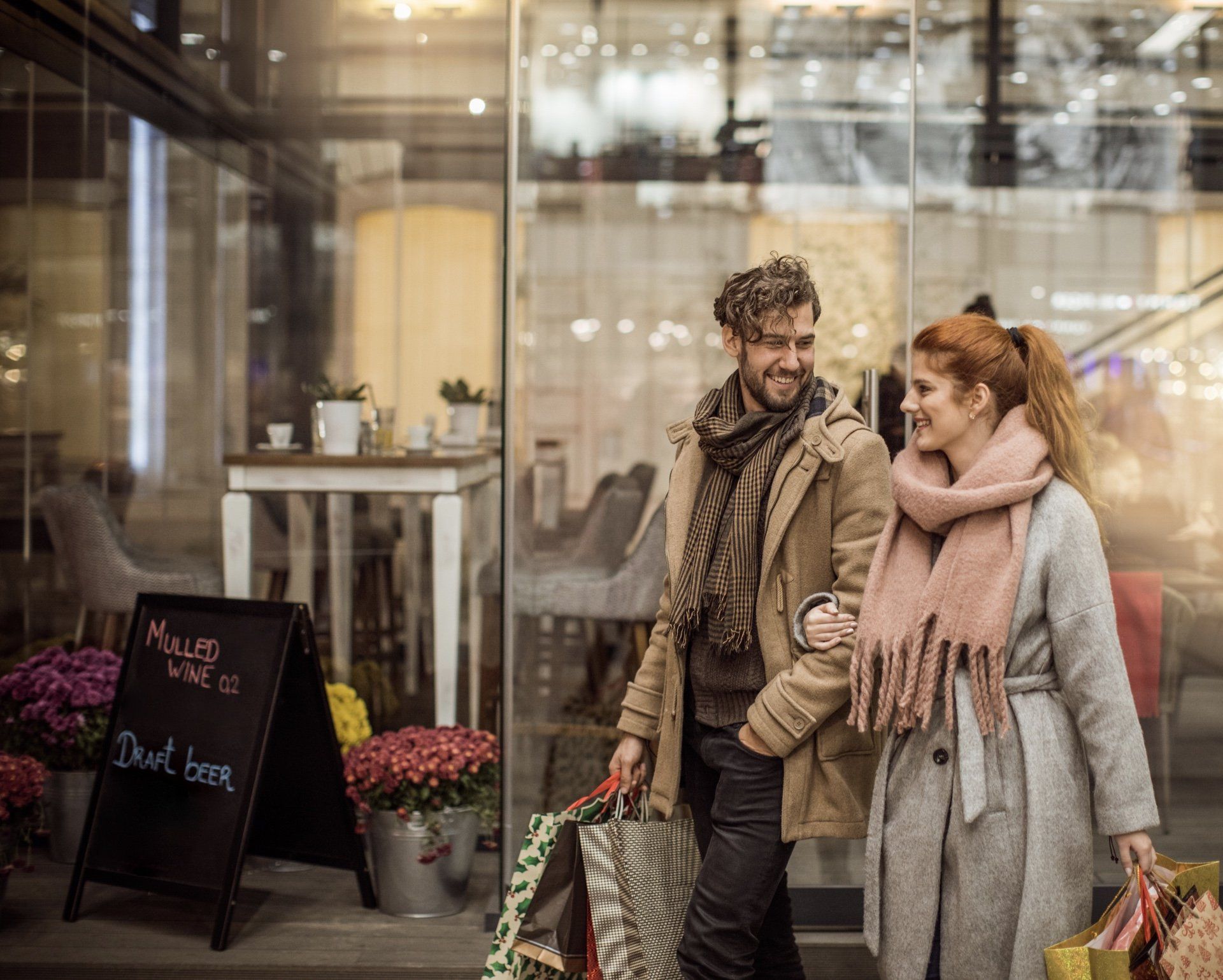A man and a woman are walking down the street with shopping bags.