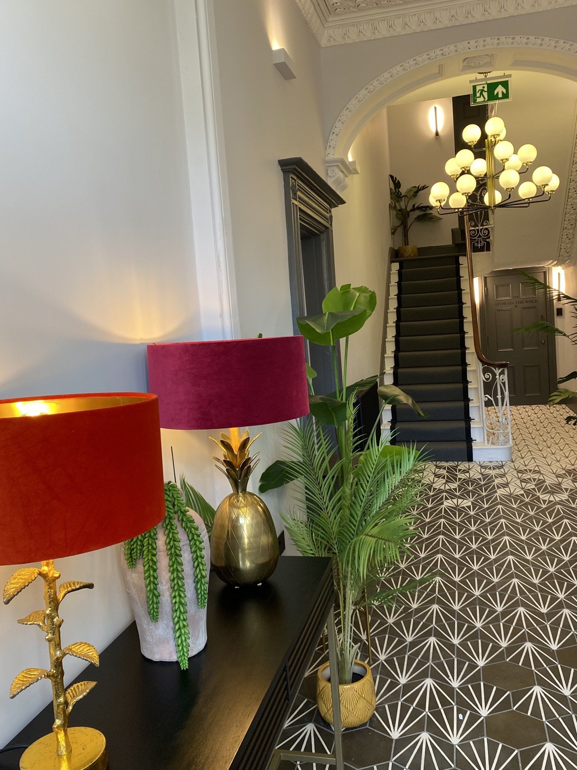 A hallway with a staircase and lamps on a table