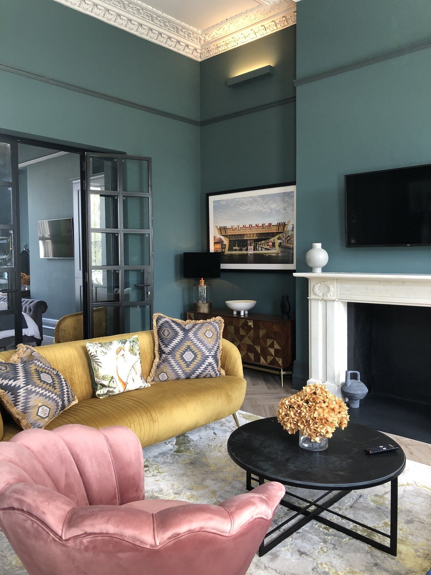 A living room with a yellow couch , pink chair , coffee table and fireplace.