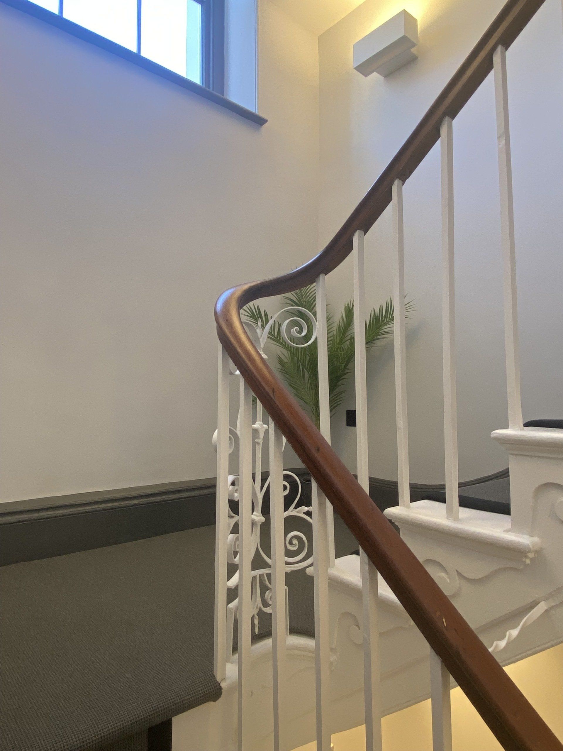 A staircase with a white railing and a wooden handrail