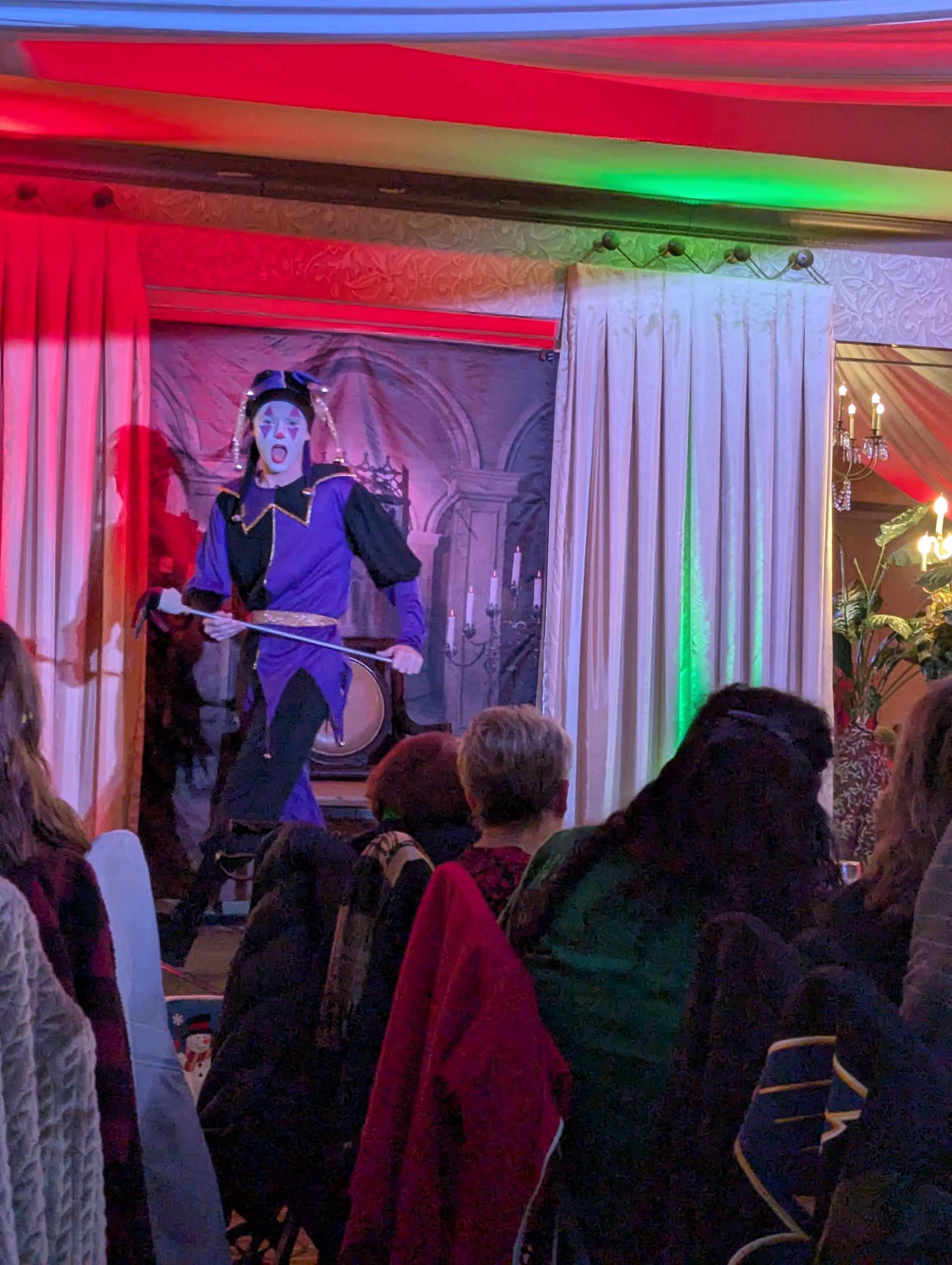Performer on stage in blue lighting, singing before an audience under red and green lights