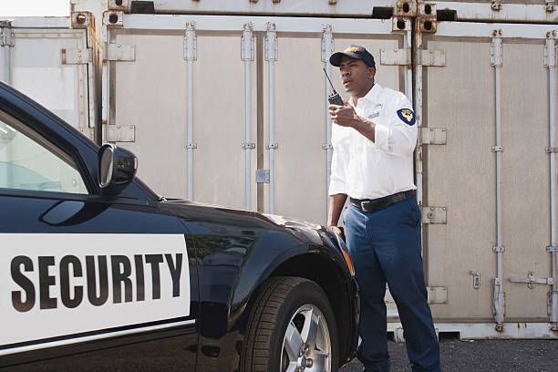 A security guard is standing next to a security car.