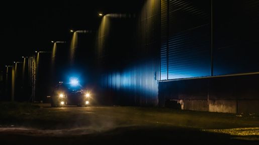 A truck is driving down a dark street at night.