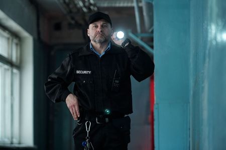 A security guard is holding a flashlight in a dark room.