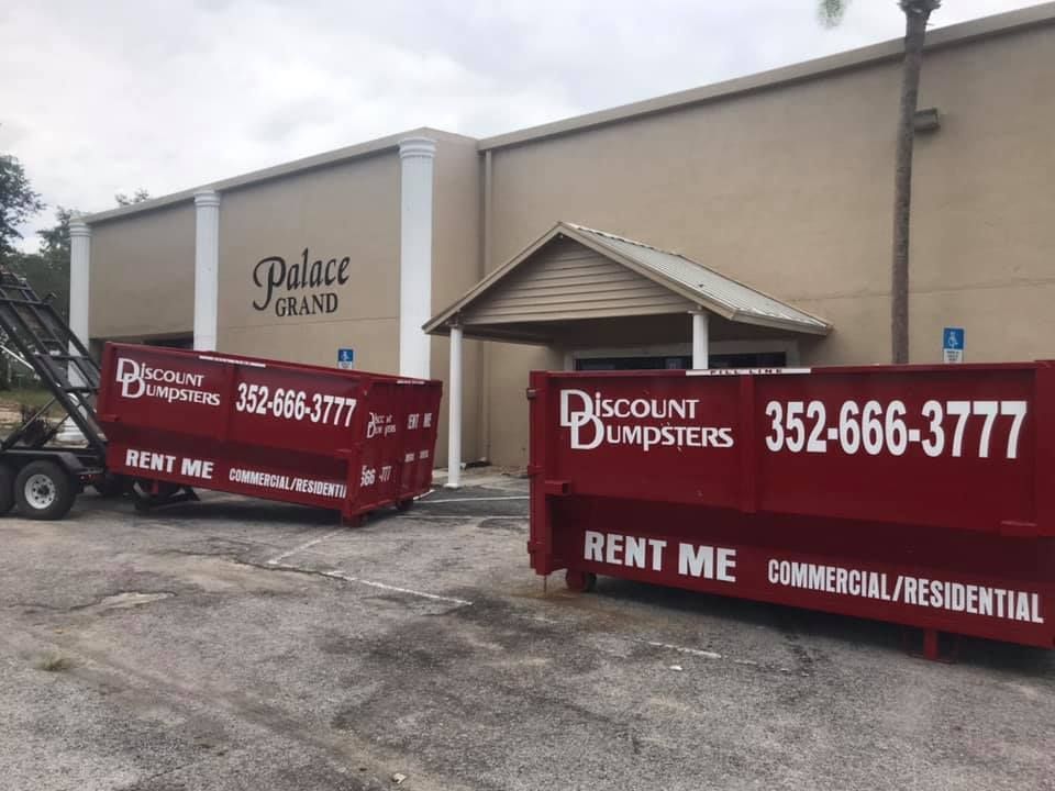 Two dumpsters are parked in front of a building.