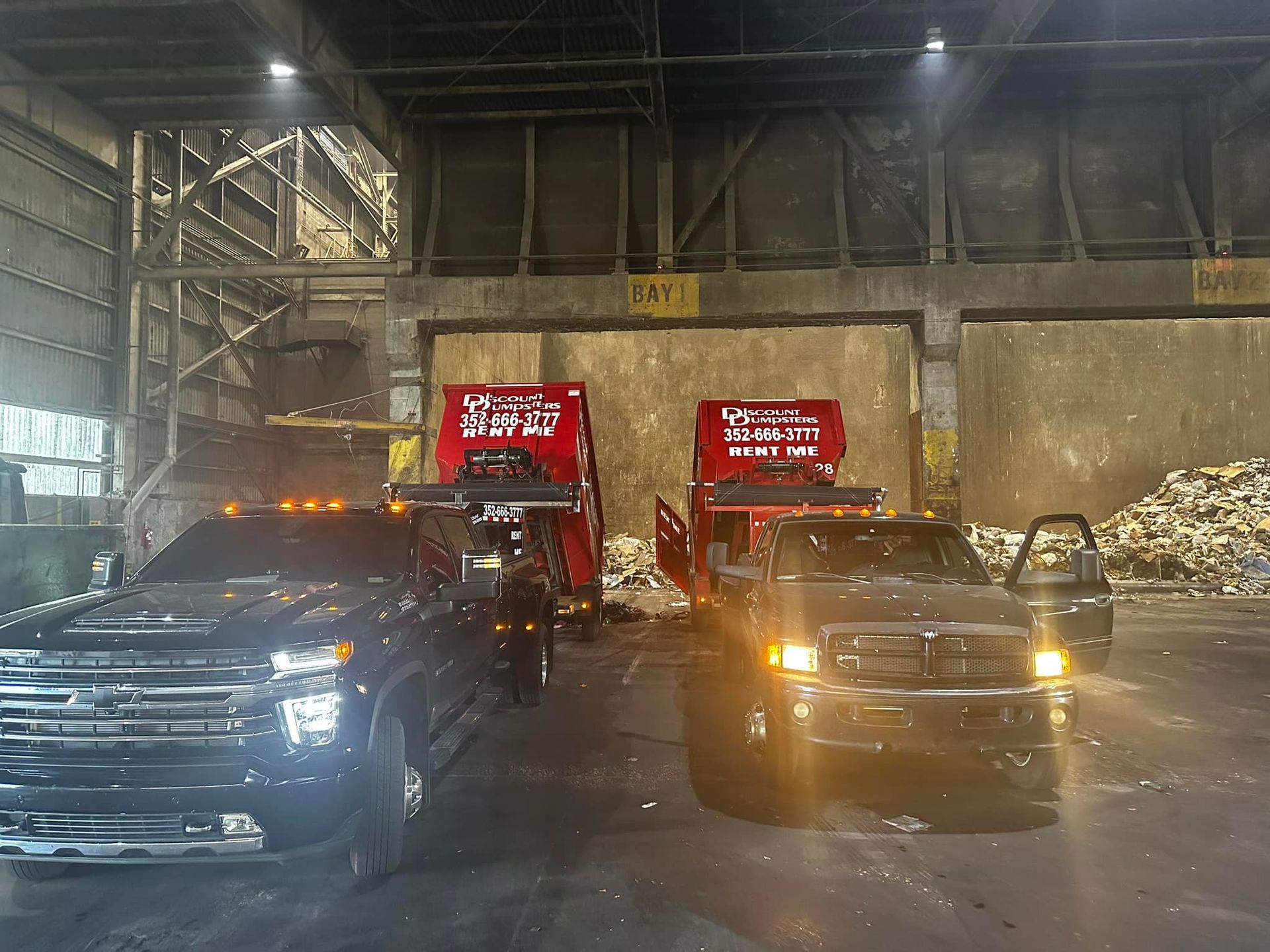 Two trucks are parked in a warehouse next to each other.