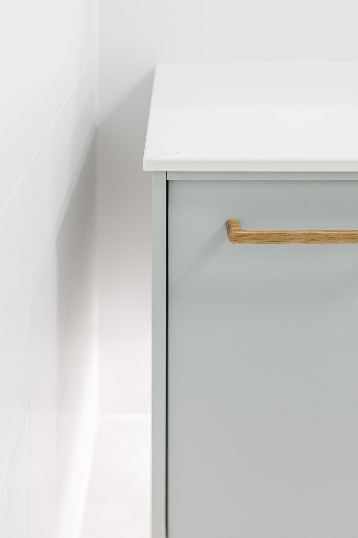 Light blue cabinet with a light wood handle, against a white wall.