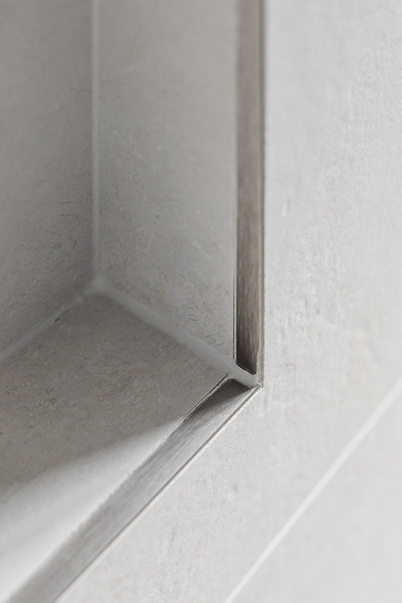 Close-up of a recessed shelf with a textured, gray, concrete-like surface. Right angle corner.