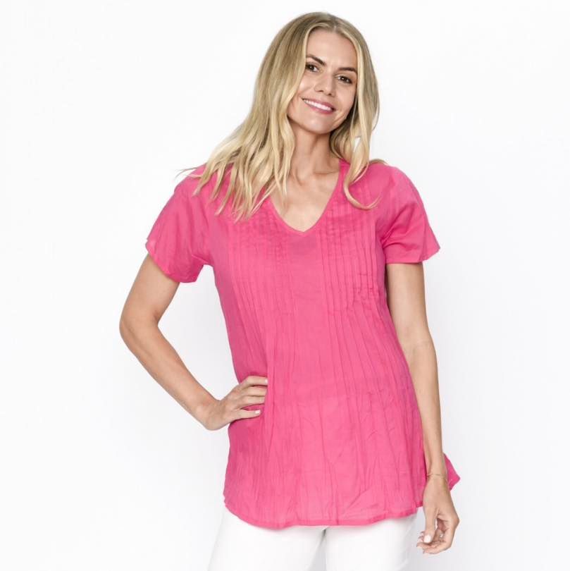Woman Wearing a Pink Top, Smiling, With Hand on Hip, in a Studio Setting— Onyx Poppy Boutique in Sunshine Coast, QLD