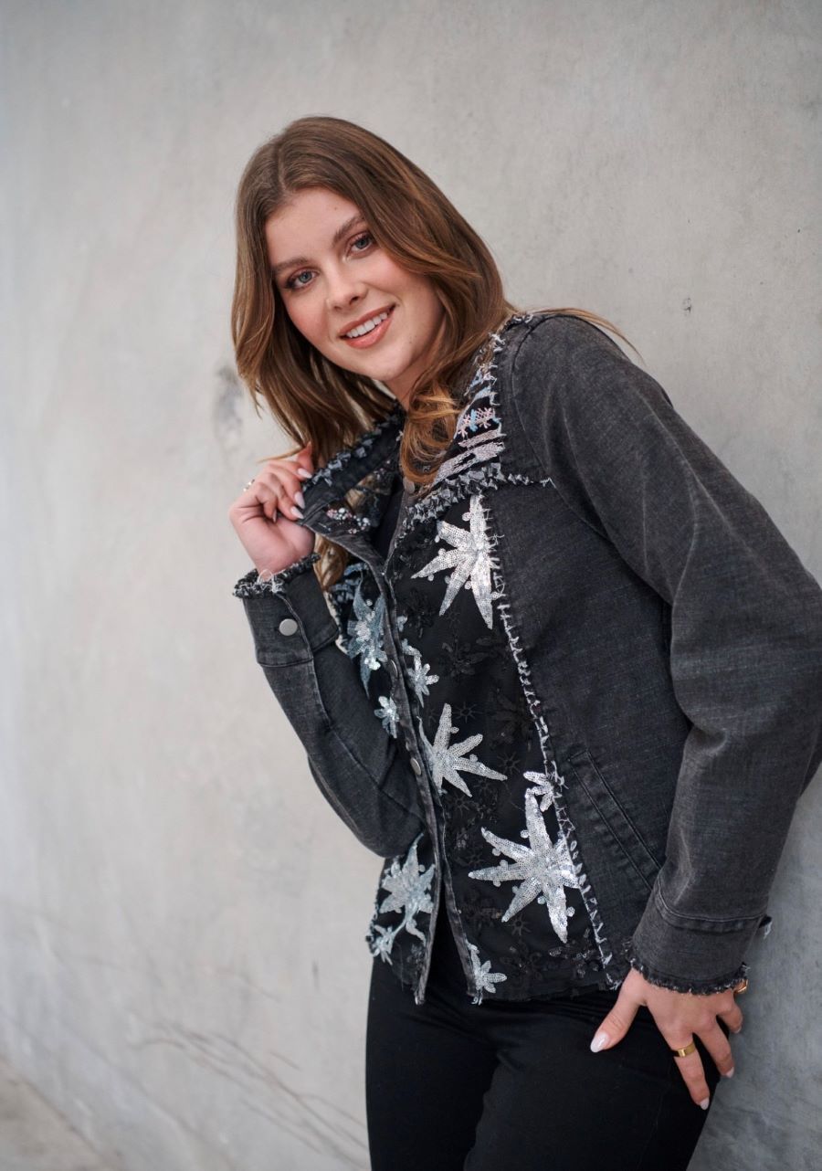 Woman in a Dark Jacket With Sequin Detail Smiles, Leaning Against a Wall — Onyx Poppy Boutique in Buderim, QLD