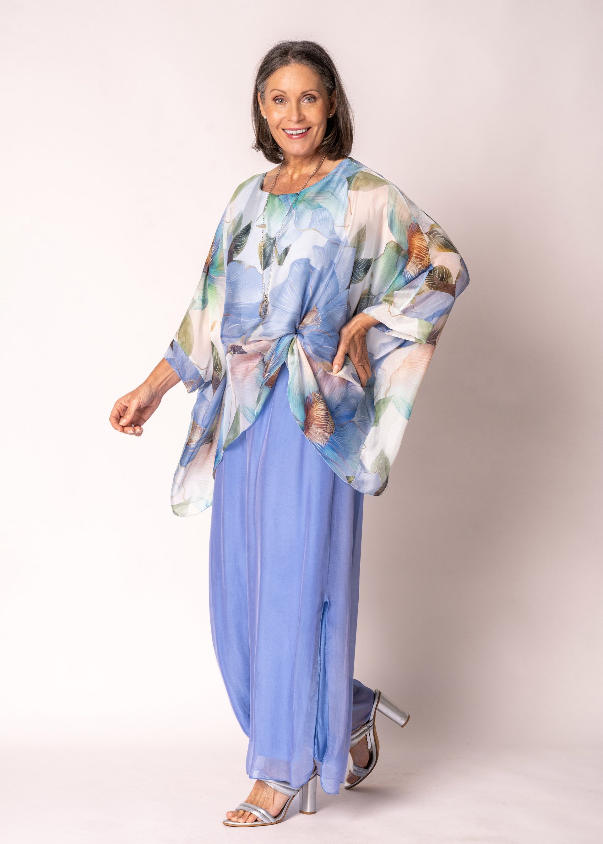 Woman in blue patterned top and pants, standing.