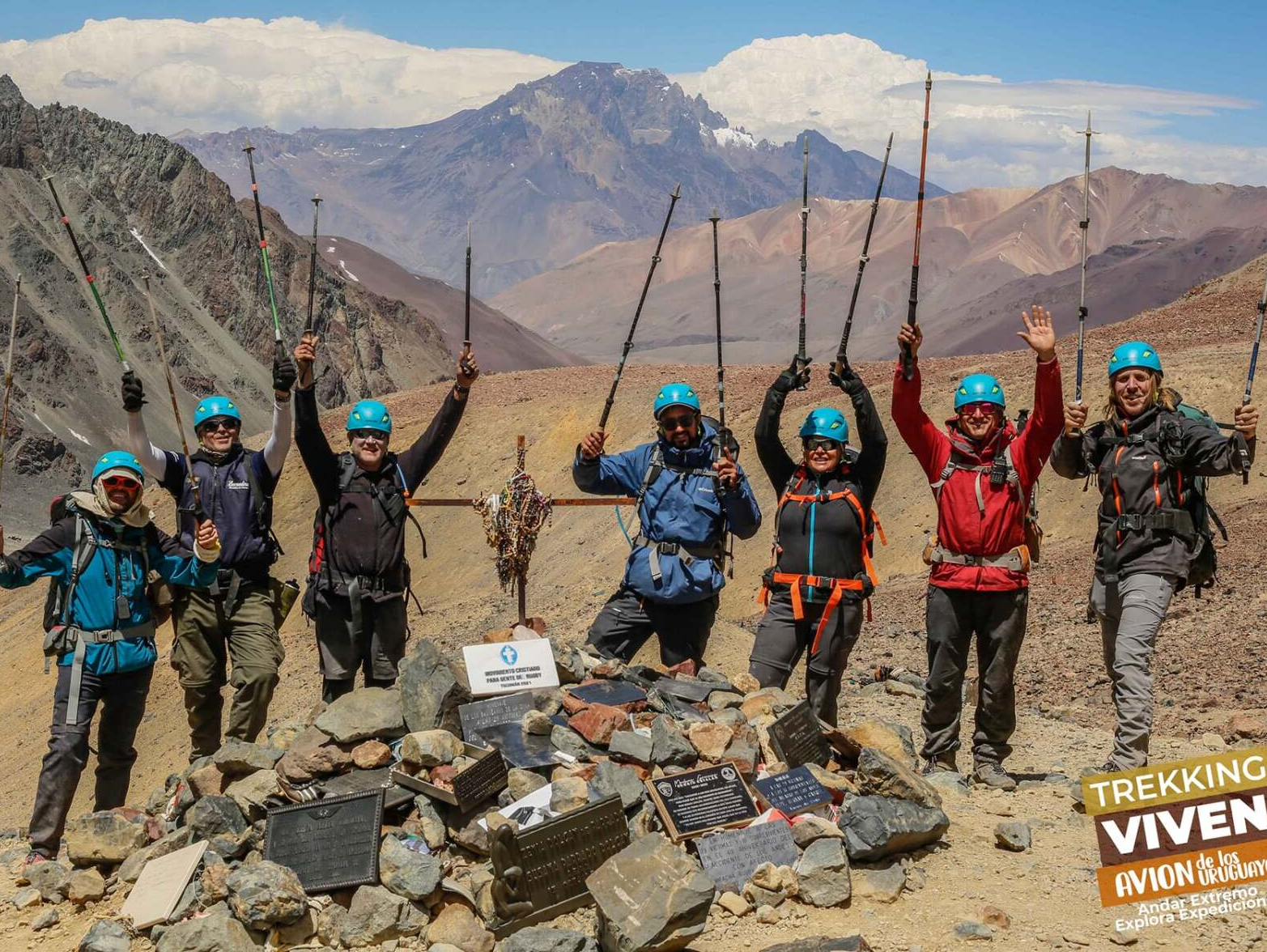 Excursionistas con ropa de colores posan con bastones de trekking en un sendero rocoso de montaña.