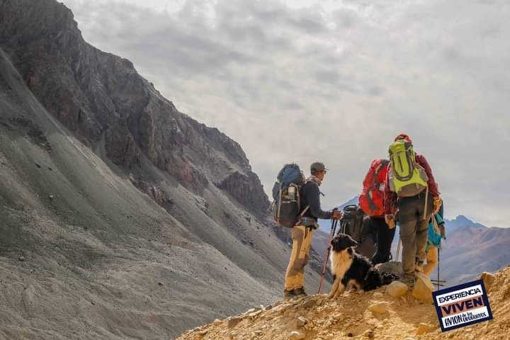 Excursionistas con mochilas descansando en una cresta rocosa de montaña bajo un cielo nublado