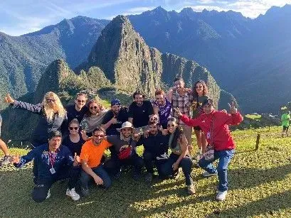 Grupo de excursionistas posando en un mirador de montaña, con un pico imponente y un valle a sus espaldas