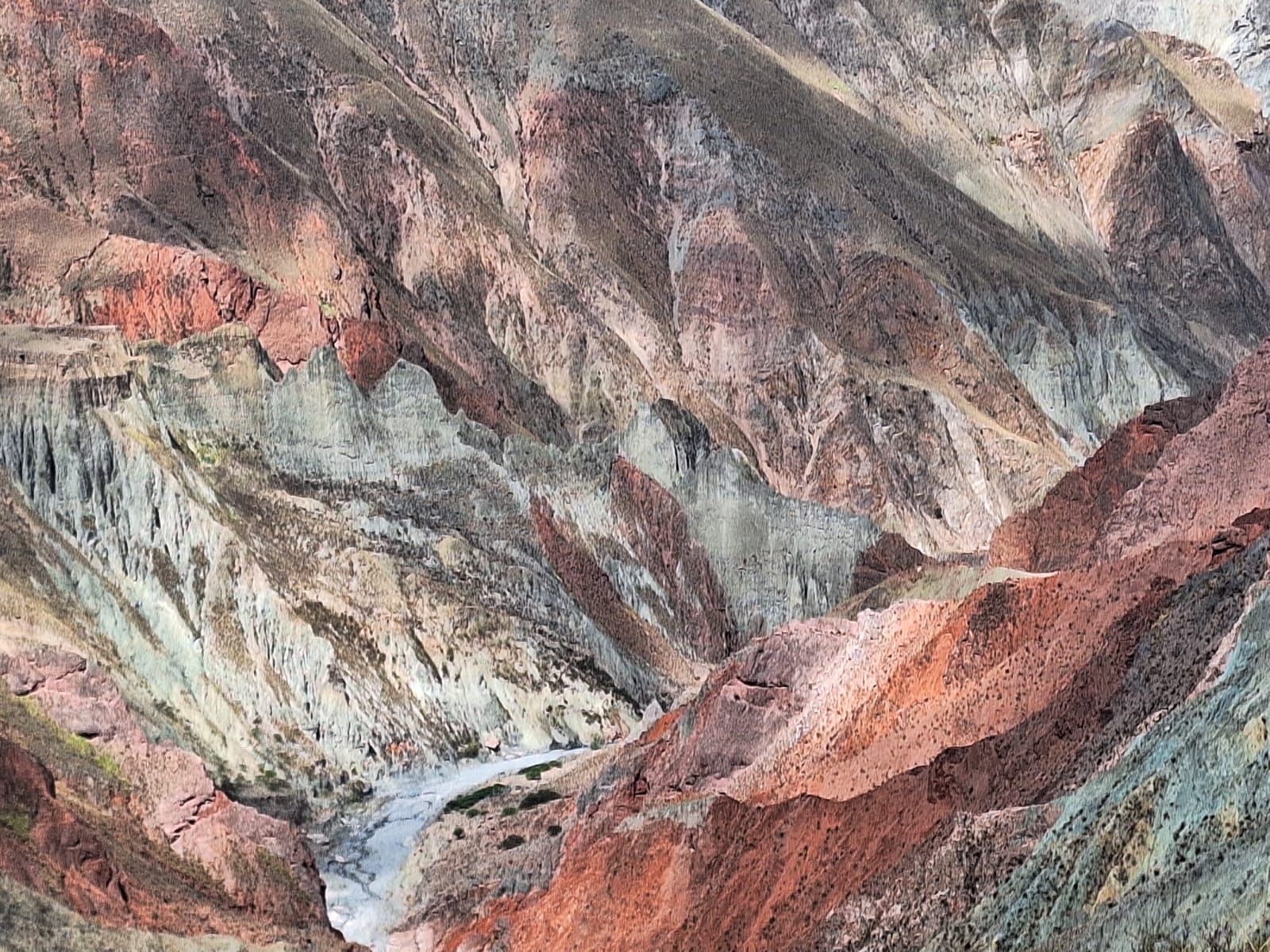 Acantilados de cañones con capas de roca roja, beige y gris bajo un cielo brumoso