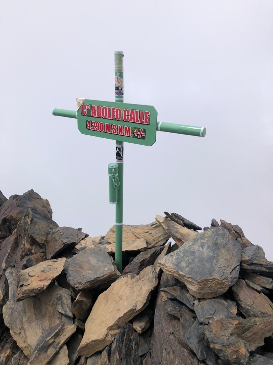 Poste indicador en una cumbre rocosa que señala el sendero hacia Mount Craig, bajo un cielo nublado
