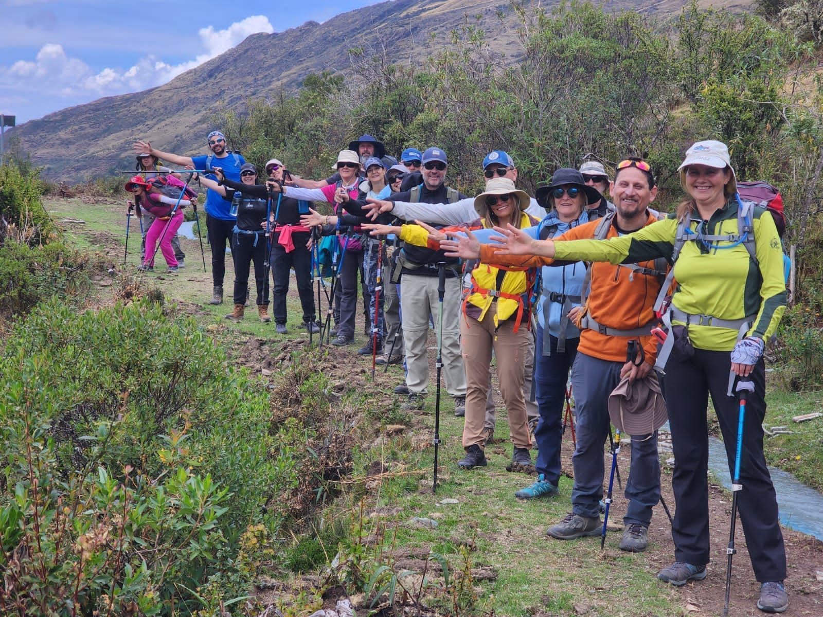 Excursionistas con chaquetas y gorros de colores hacen fila en un sendero de montaña y extienden los bastones.