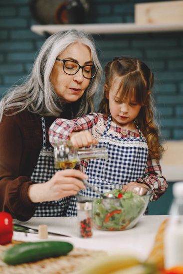 Woman and child baking together, stirring ingredients in a kitchen with fresh vegetables on the counter