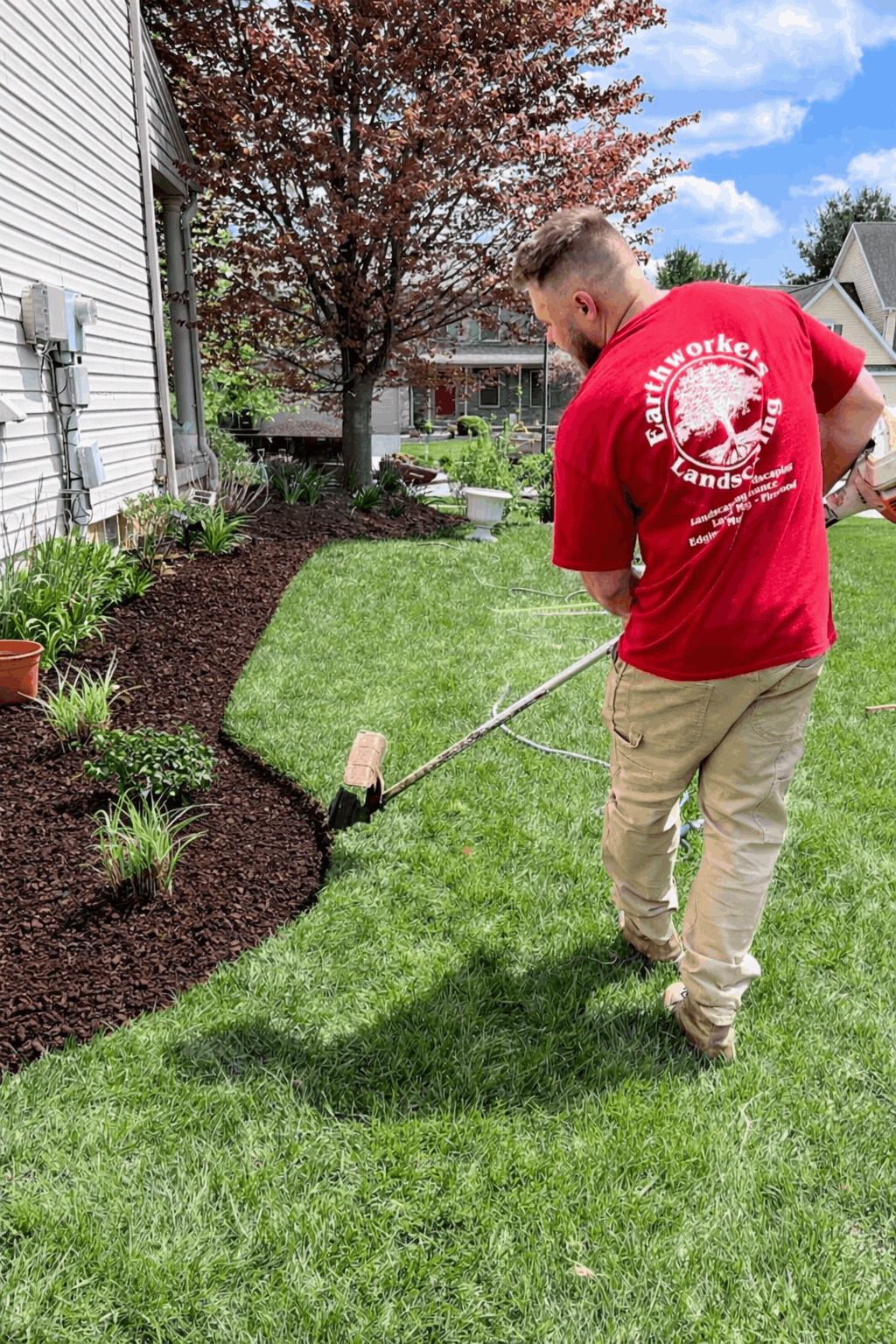 A white house with a purple door and a garden in front of it.
