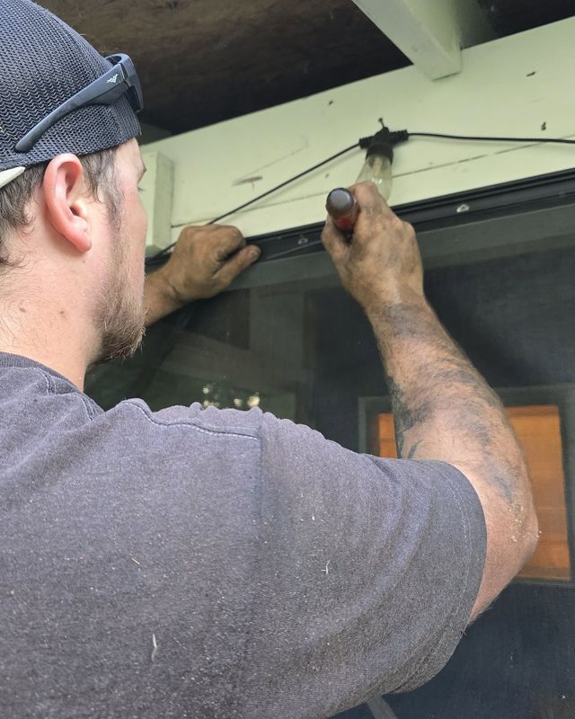 Person using a tool to repair a window screen frame outdoors