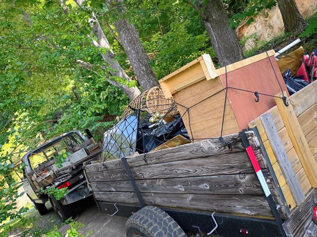 Loaded trailer with lumber and debris in a wooded yard