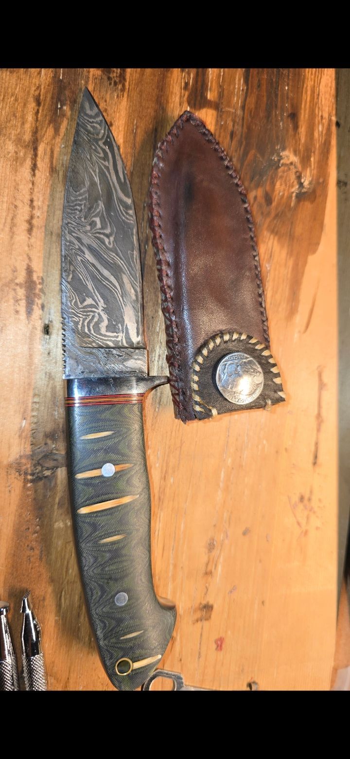 Two knives in sheaths hanging on a wooden wall