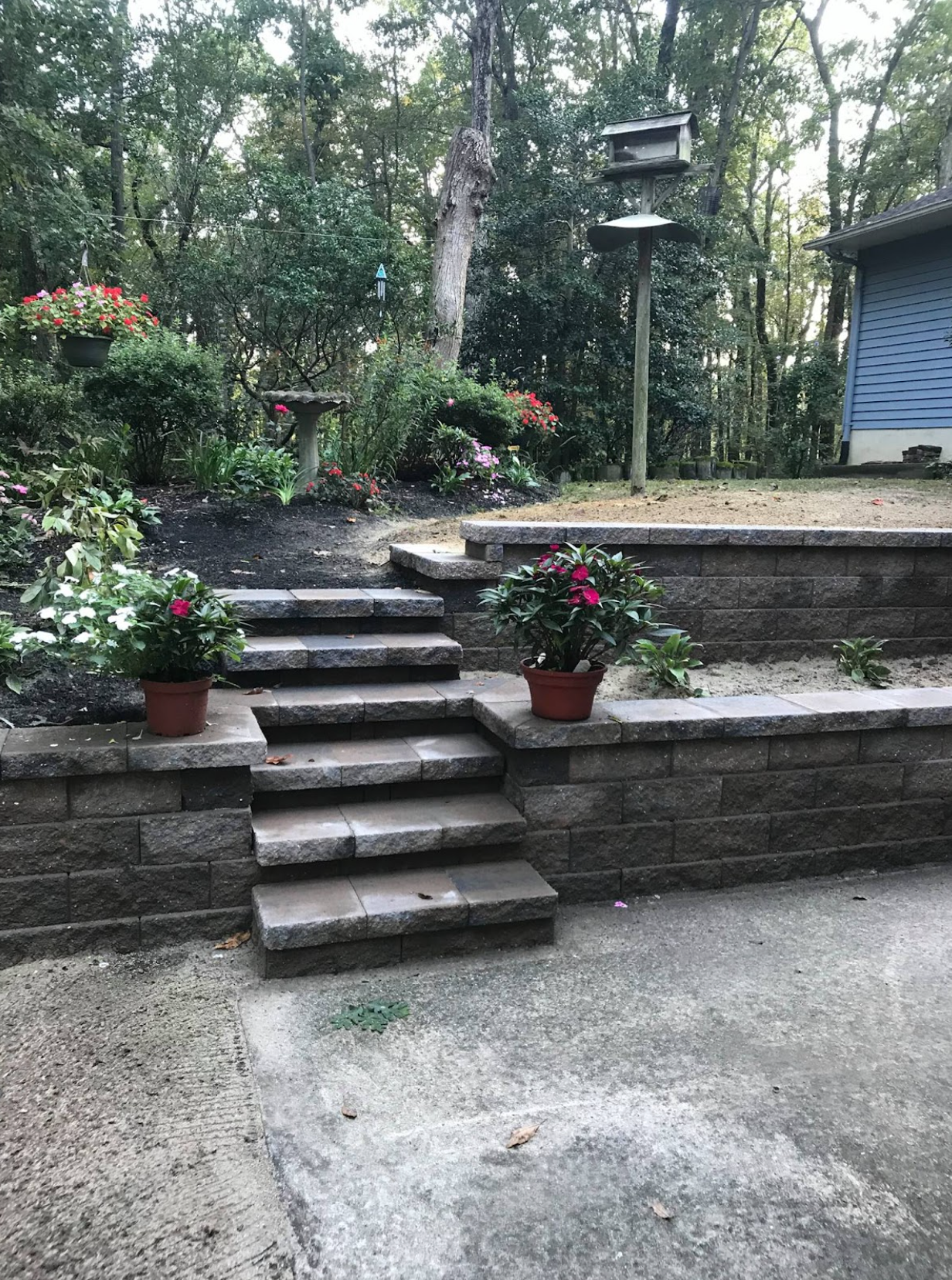 A brick wall with stairs leading up to it and flowers in pots.
