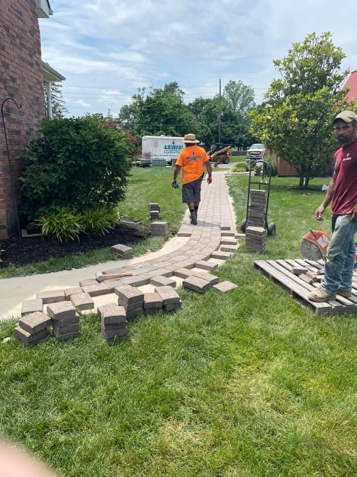 A couple of men are walking down a sidewalk in a yard.