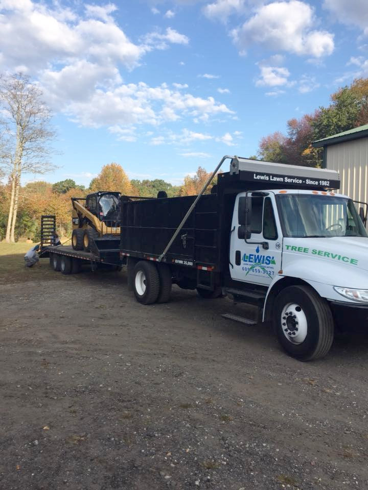 A dump truck is parked next to a trailer with a bulldozer on it.