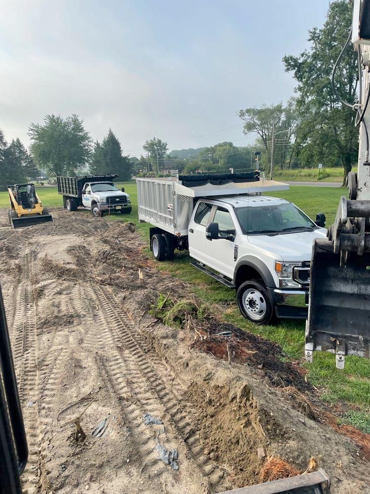 A dump truck is parked next to a bulldozer on a dirt road.