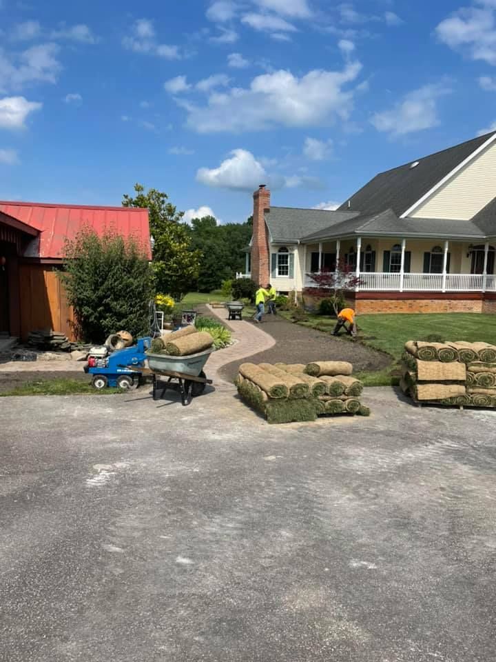 A group of people are working on a lawn in front of a house.