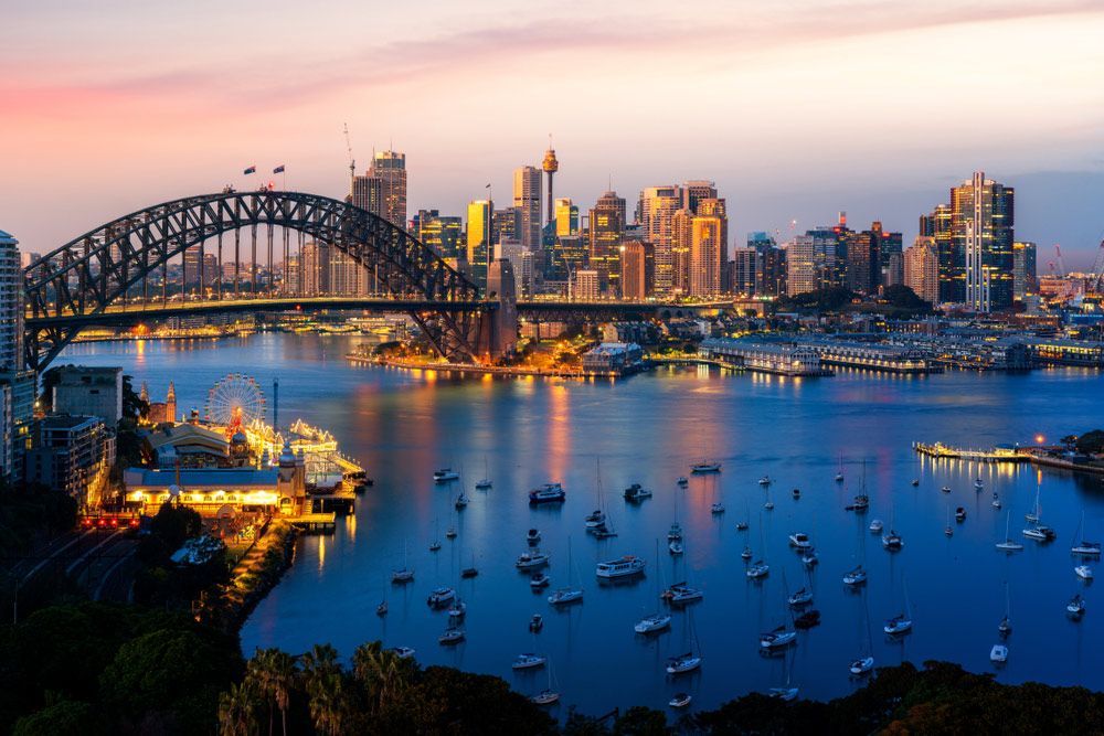 A Bridge over a body of water with boats in it and a city in the Background — Precast Concrete Solutions in Sydney, NSW