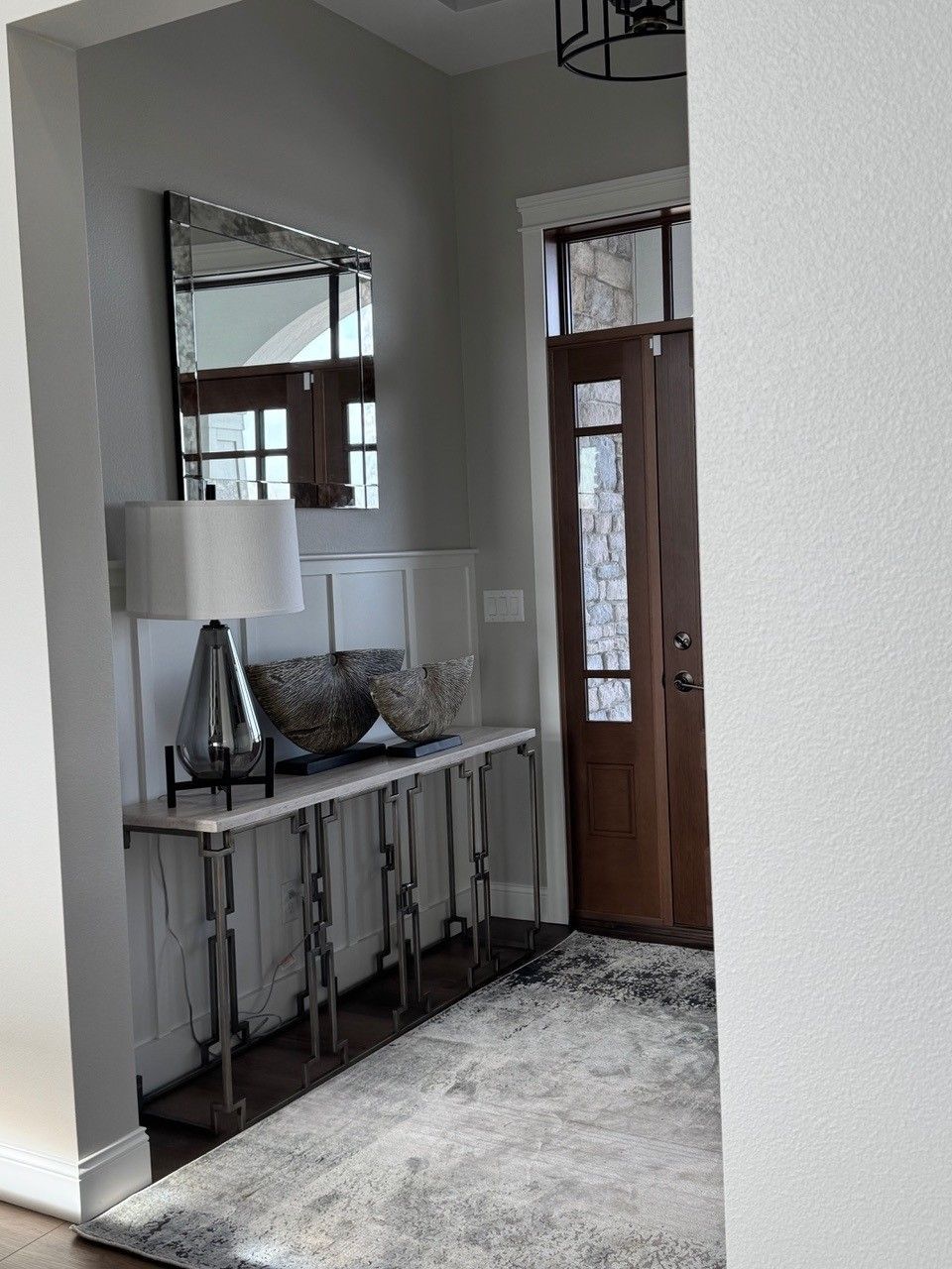 Modern entryway with console table, mirror, lamp, rug, and wooden front door