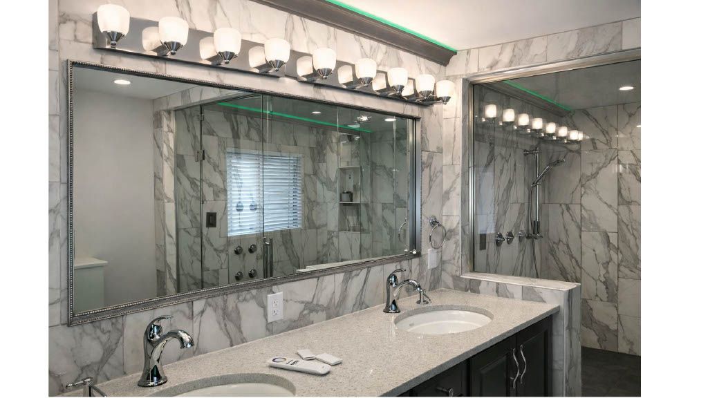 Marble bathroom vanity with large mirror, sink, and bright vanity lights above.