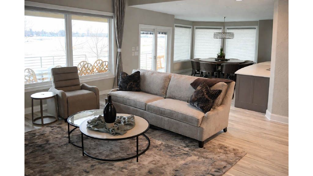 Bright living room with beige sofa, round coffee tables, patterned rug, and open kitchen in background